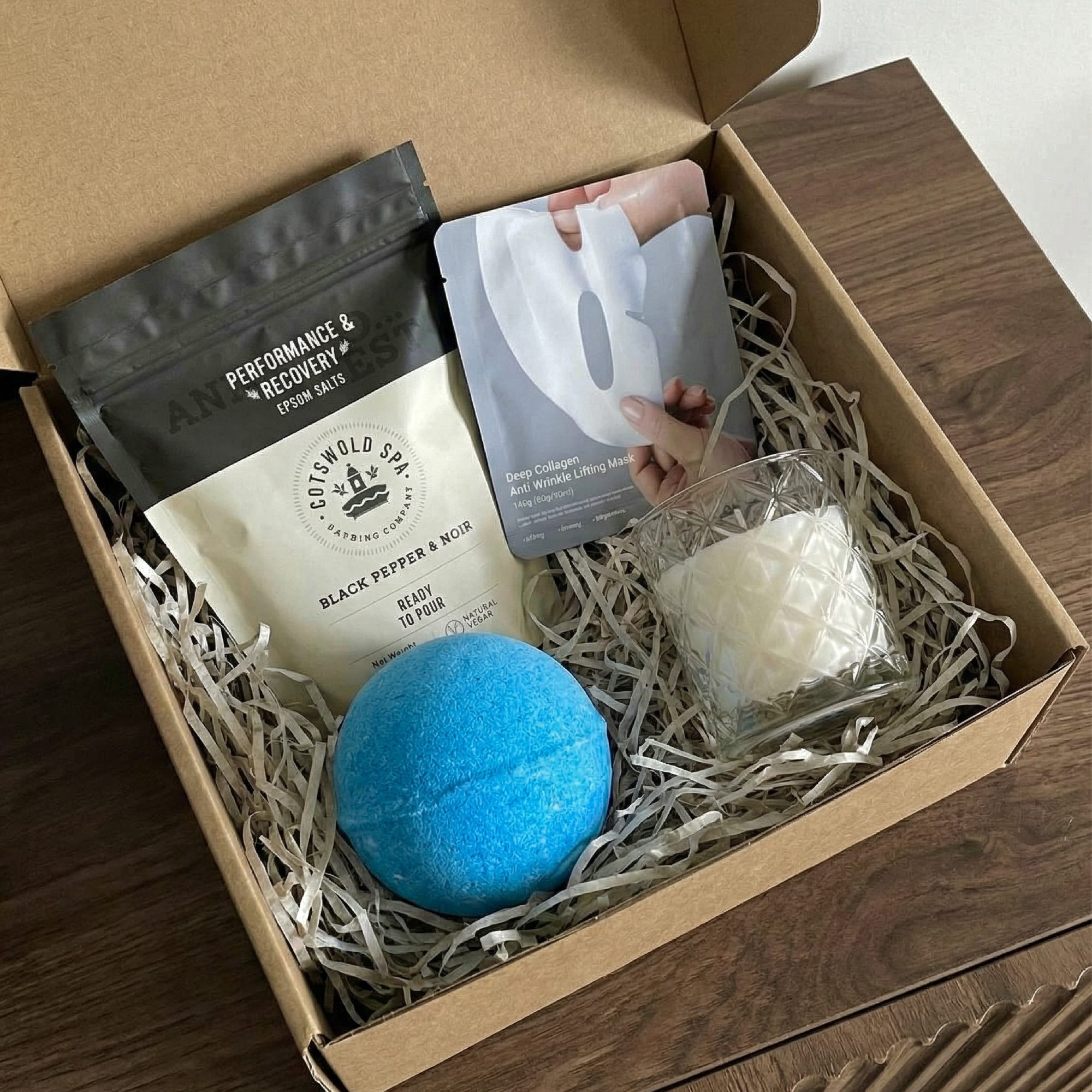 Unboxed spa gift set in cardboard box with epsom salts, bath bomb, face mask, candle, and straw filling
