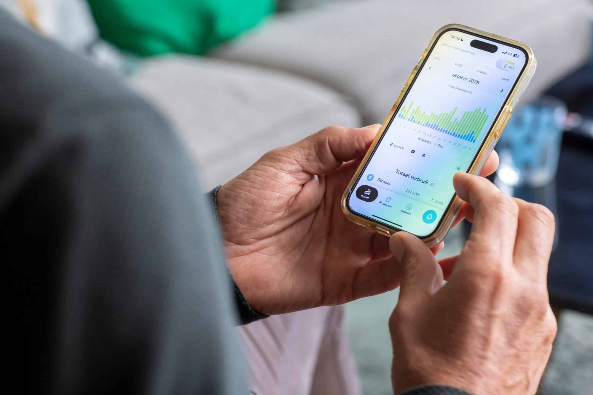 Handen houden gouden smartphone met energieverbruikgrafiek en groene statistieken