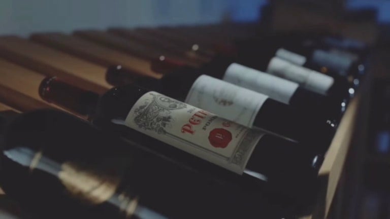 Weinflaschen mit weißen Etiketten in einem Weinregal, eine Flasche mit rotem Siegel im Fokus