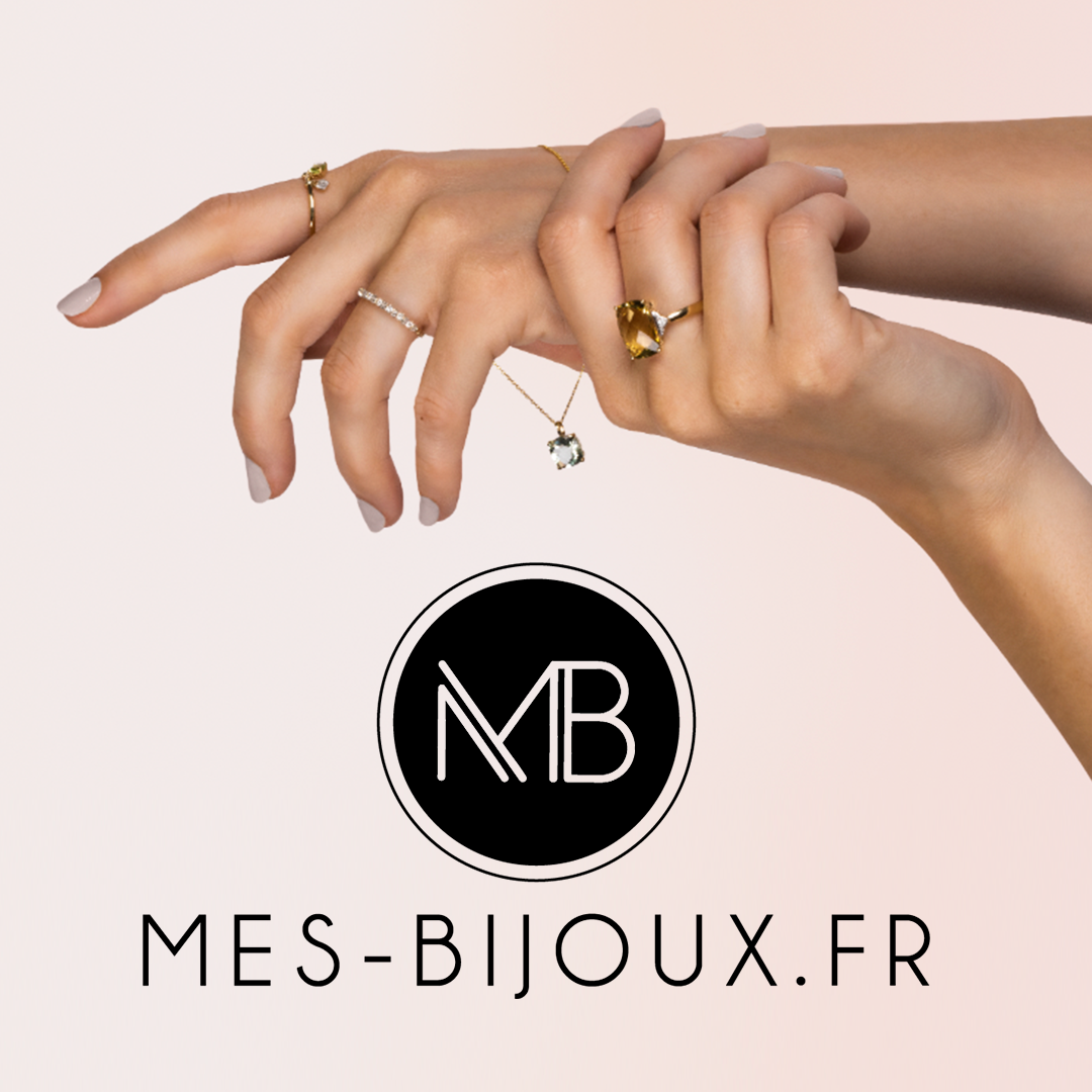 Mains portant des bagues en or et collier avec cristaux colorés sur fond beige clair