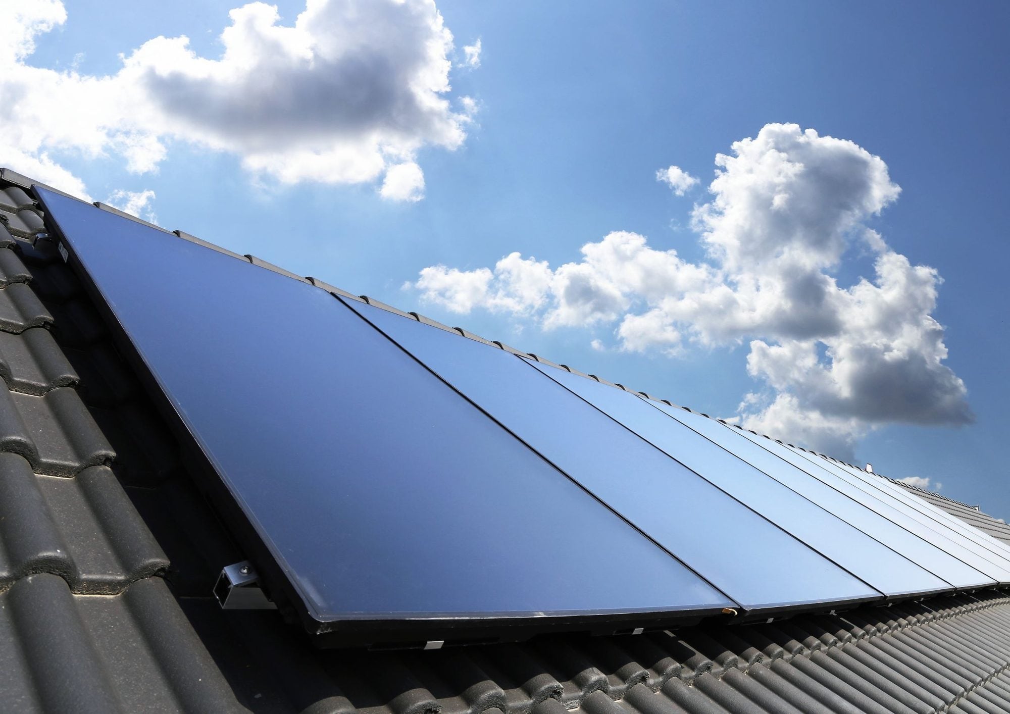 Blauwe zonnepanelen op dak onder bewolkte hemel