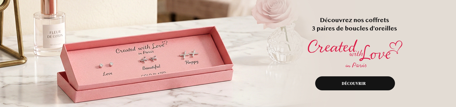 Coffret cadeau rose avec trois paires de boucles d'oreilles en or blanc sur fond marbre