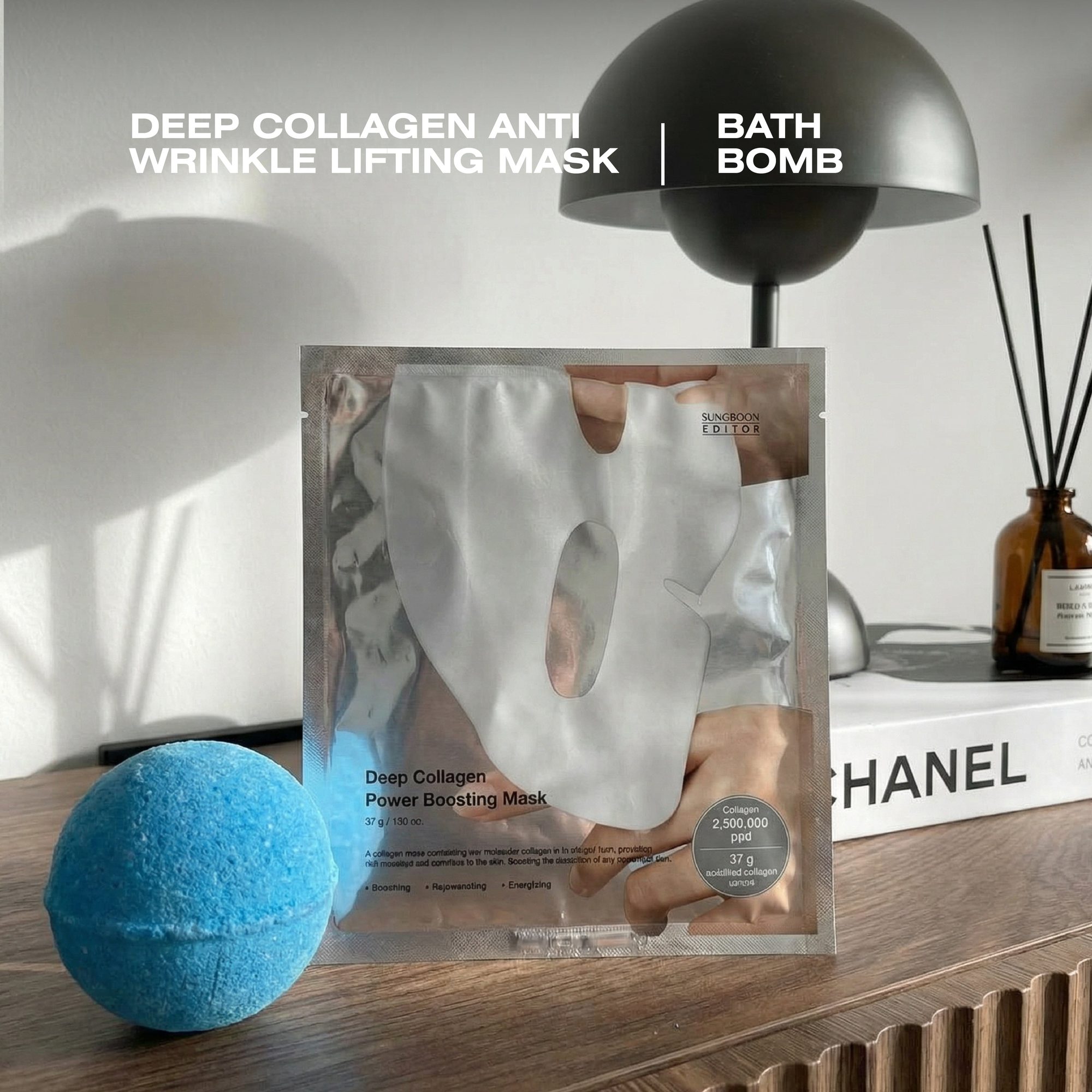 Blue bath bomb next to white face mask packet and diffuser on wooden surface with lamp in background